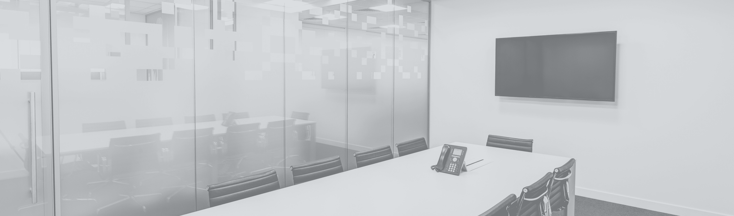 an empty conference room with a desk and TV screen
